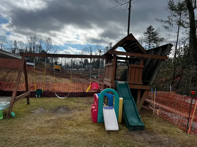 Old wooden backyard playset with swings and a slide, ready to be torn down and hauled away